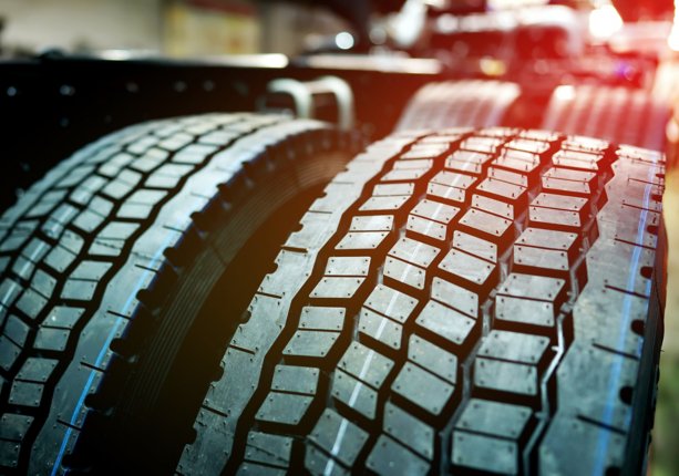 Tire tread of large rubber wheel. Tires for truck in Assembly line. Warehouse with tires for Heavy duty trucks in lorry industrial plant.  Rubber tire for truck. New Tyres for lorry. Wheel assembly. 