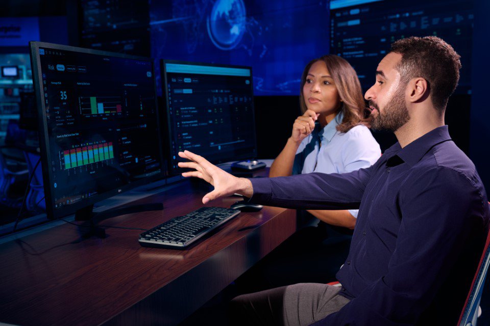 Two employees discussing looking at monitor screen