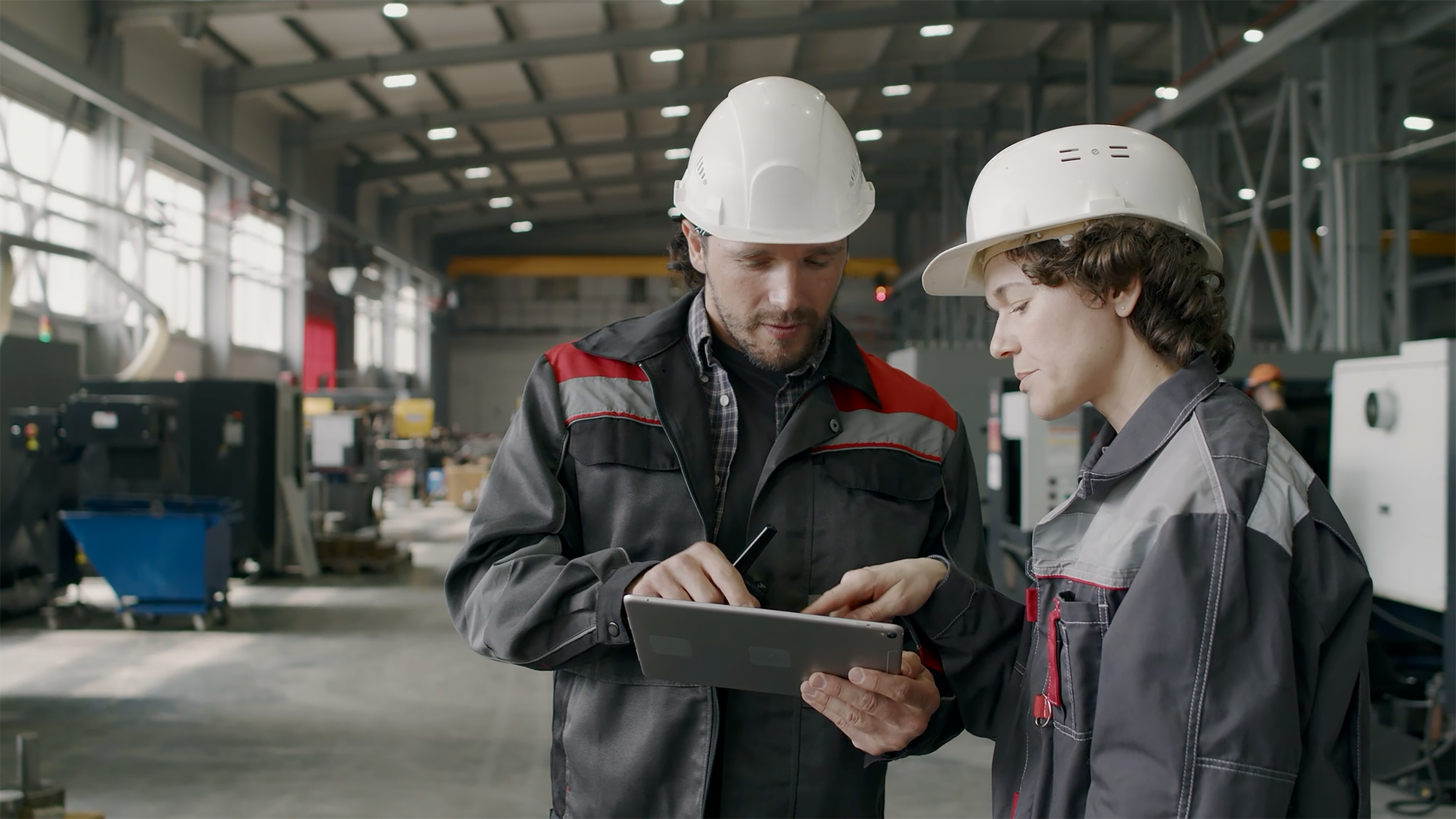 two engineers consult tablet hard hats industrial facility
