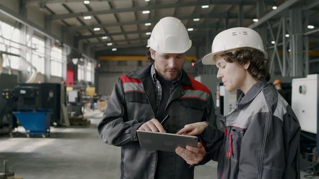 two engineers consult tablet hard hats industrial facility