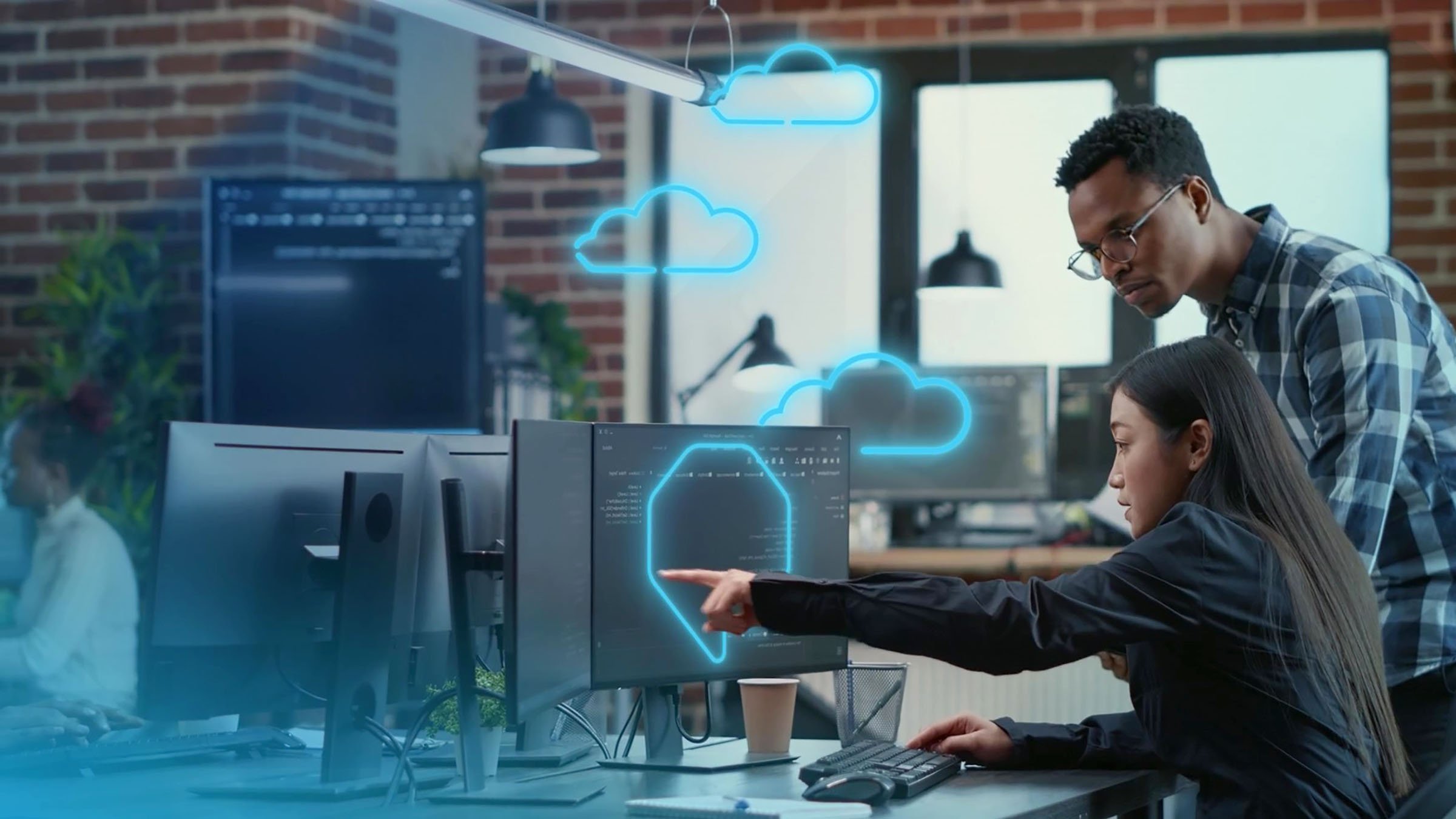 Two people looking at monitor, woman is pointed to screen, cloud icons