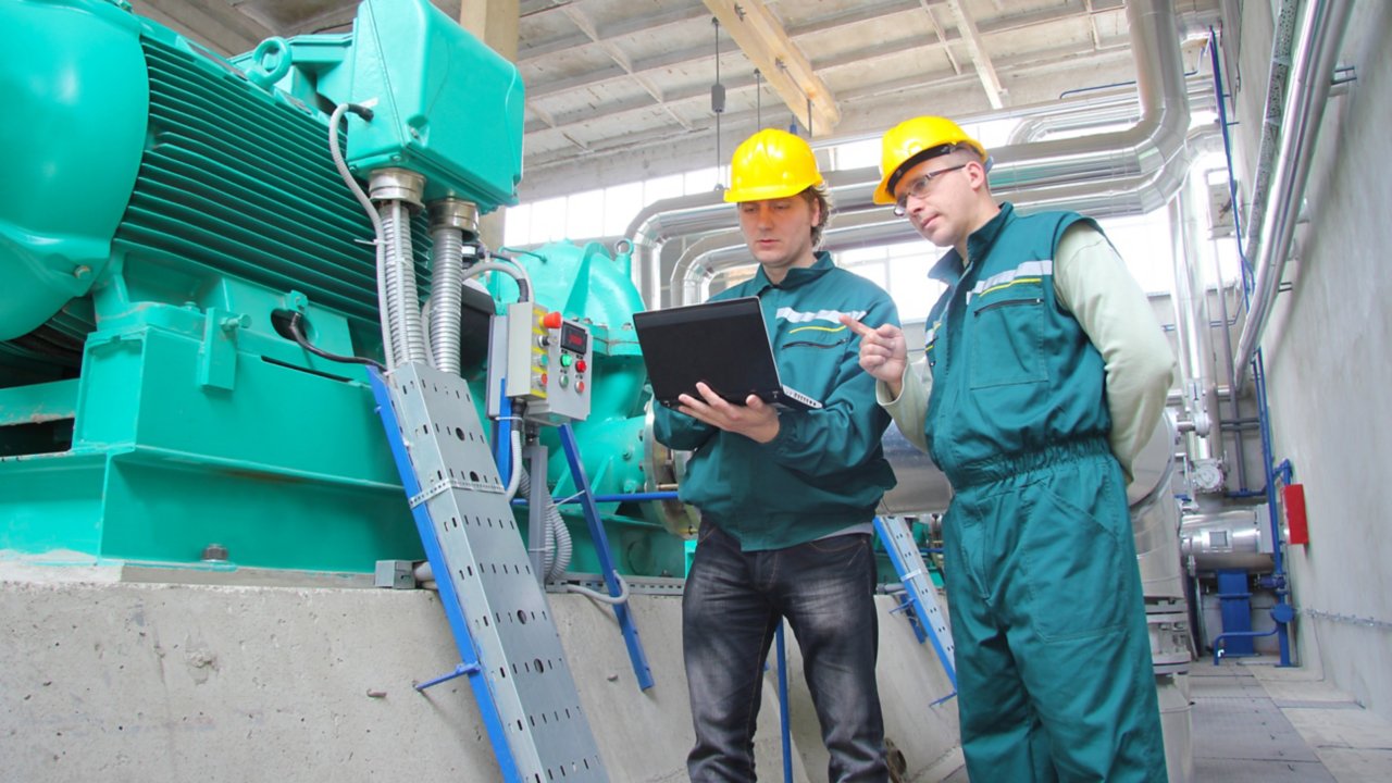 Two workers with laptop at power plant