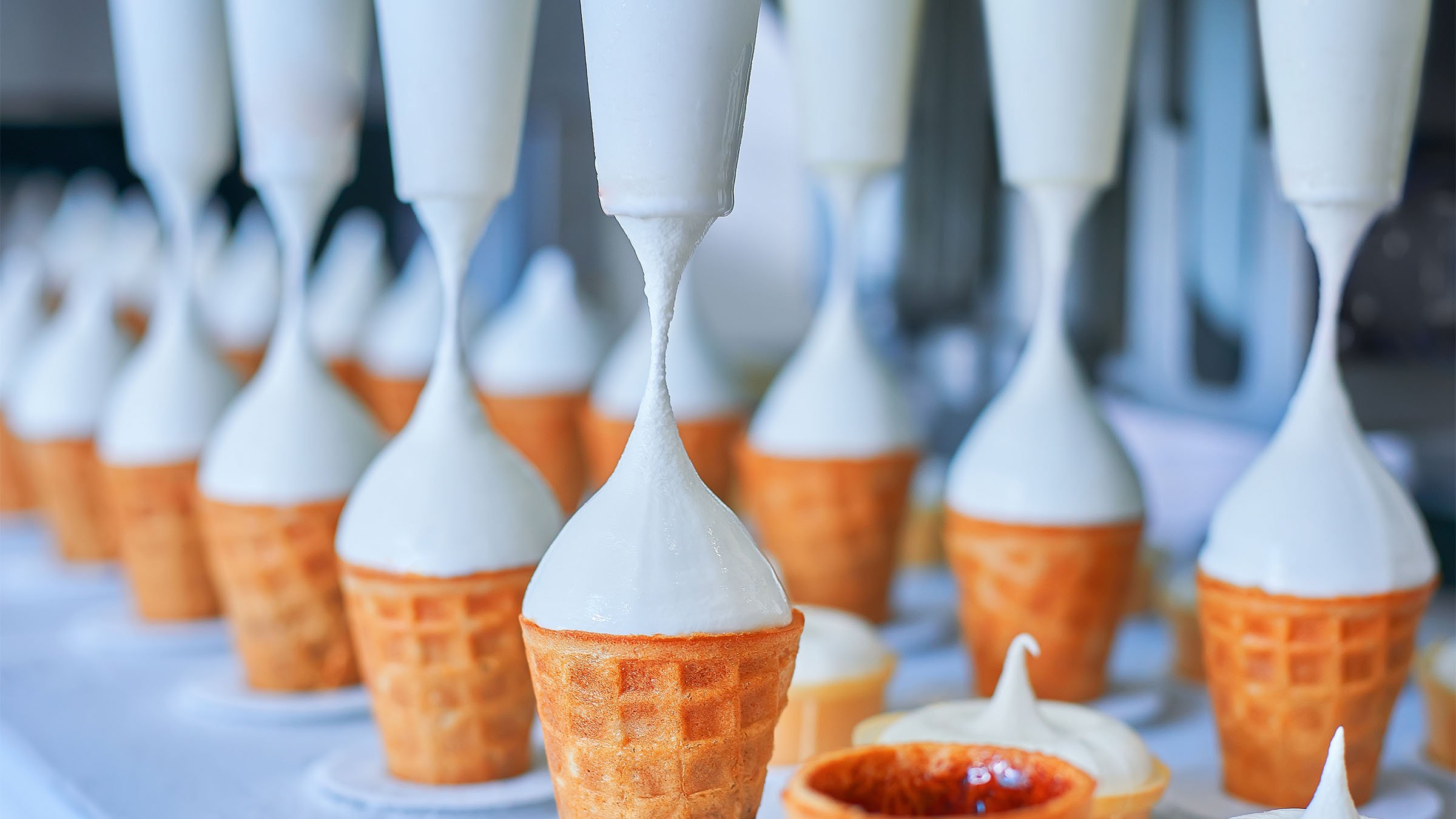 Ice-cream dairy factory - conveyor belt with icecream cones at modern food processing factory. Manufacturing, dairy industry.