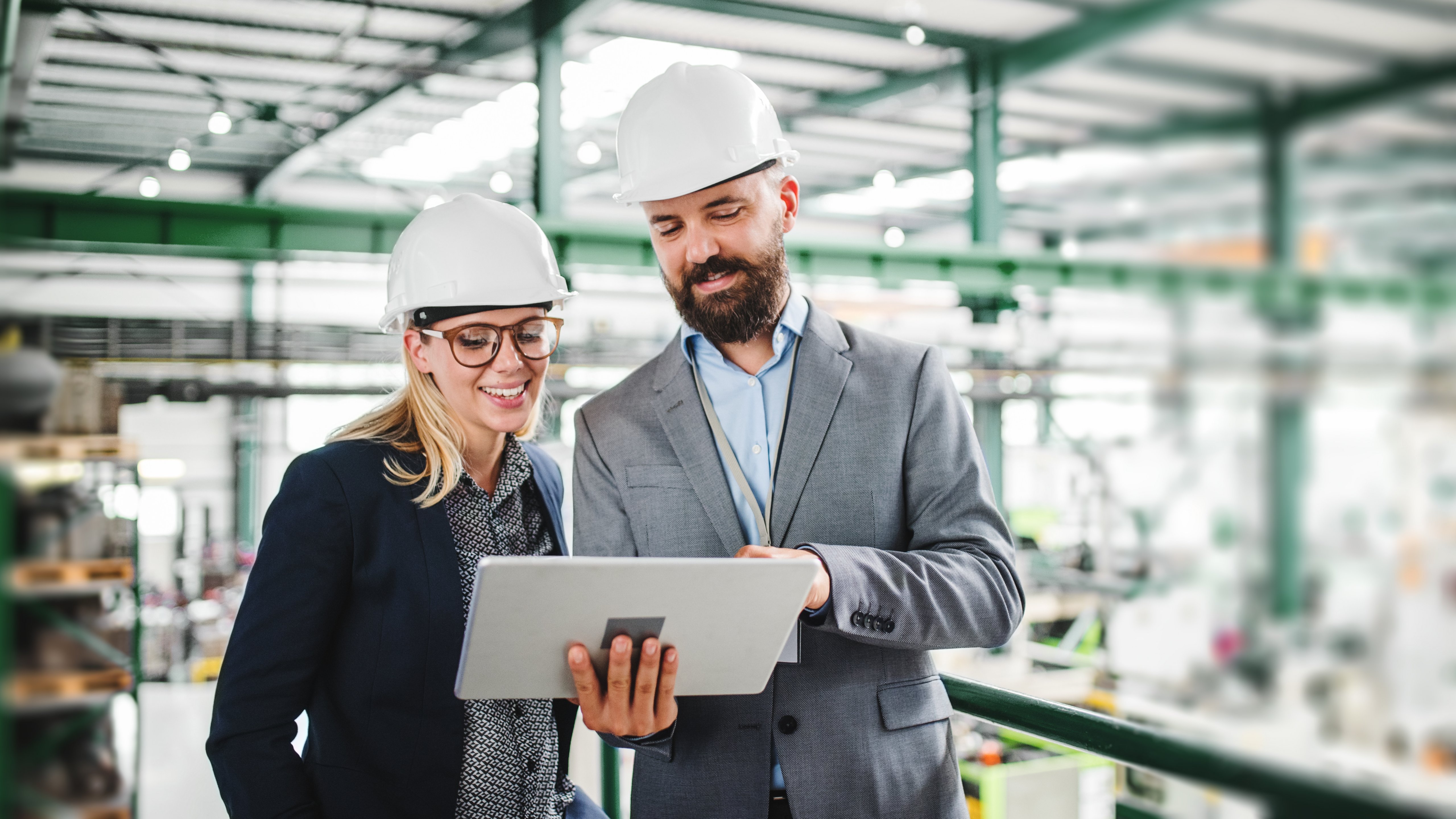 A portrait of a mature industrial man and woman engineer with tablet in a factory, working.