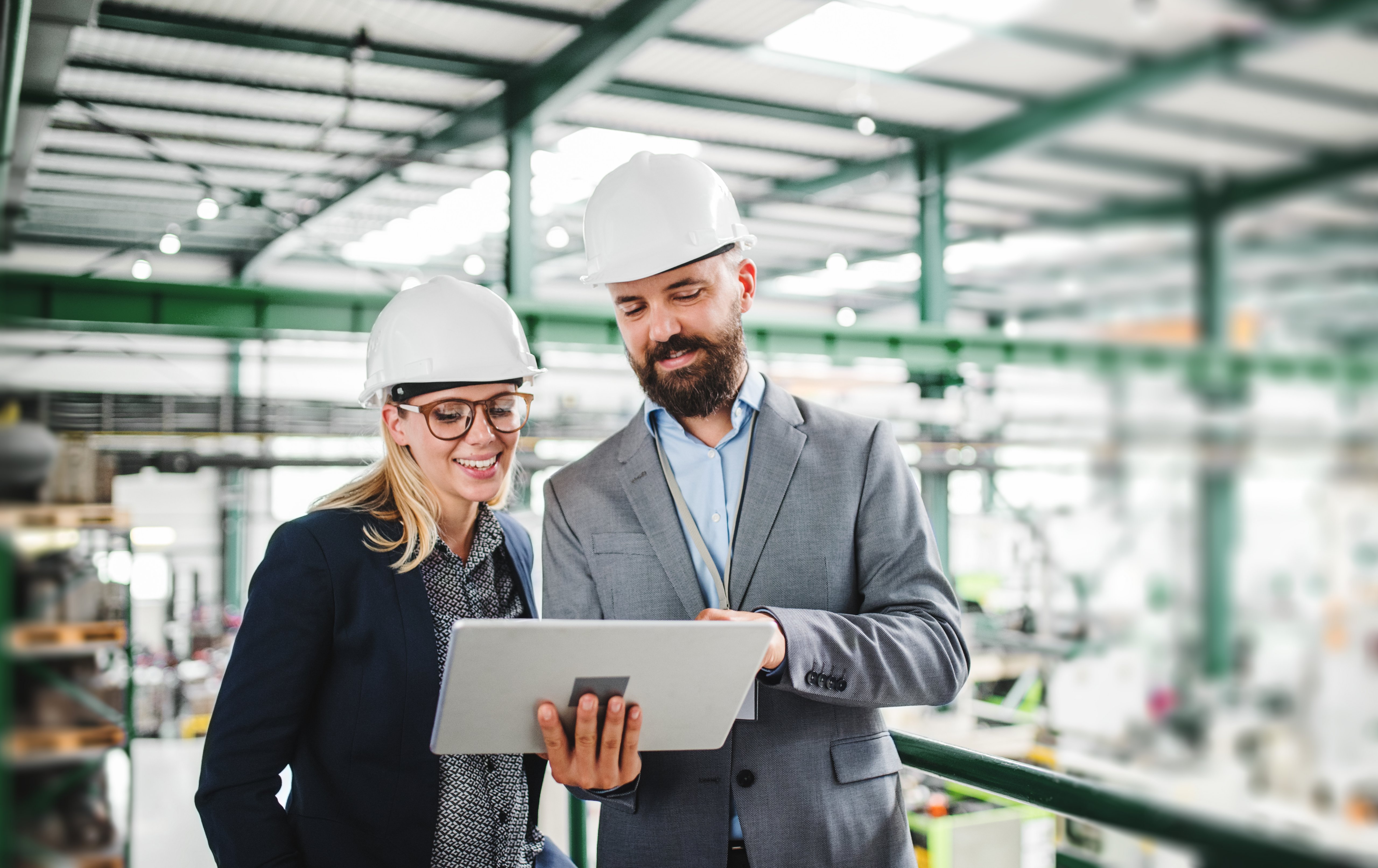 A portrait of a mature industrial man and woman engineer with tablet in a factory, working.
