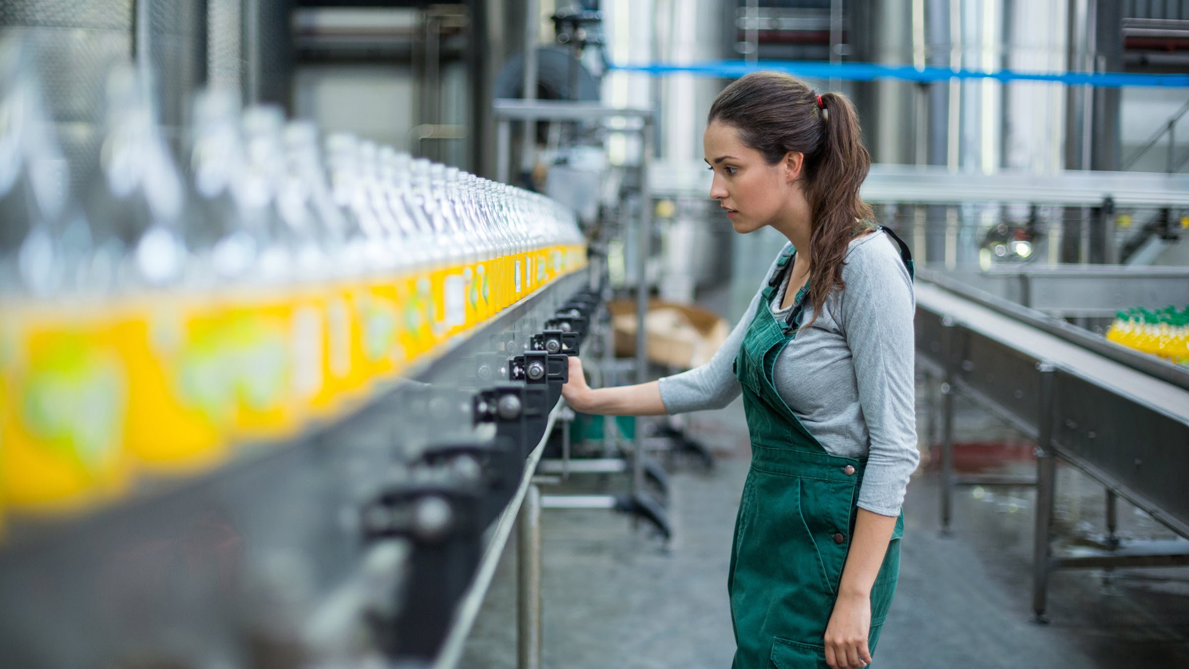 woman monitors bottle production at factory