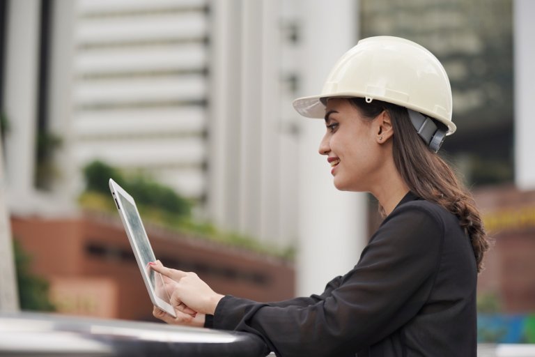 woman engineer wearing white helmet at construction site use computer tablet