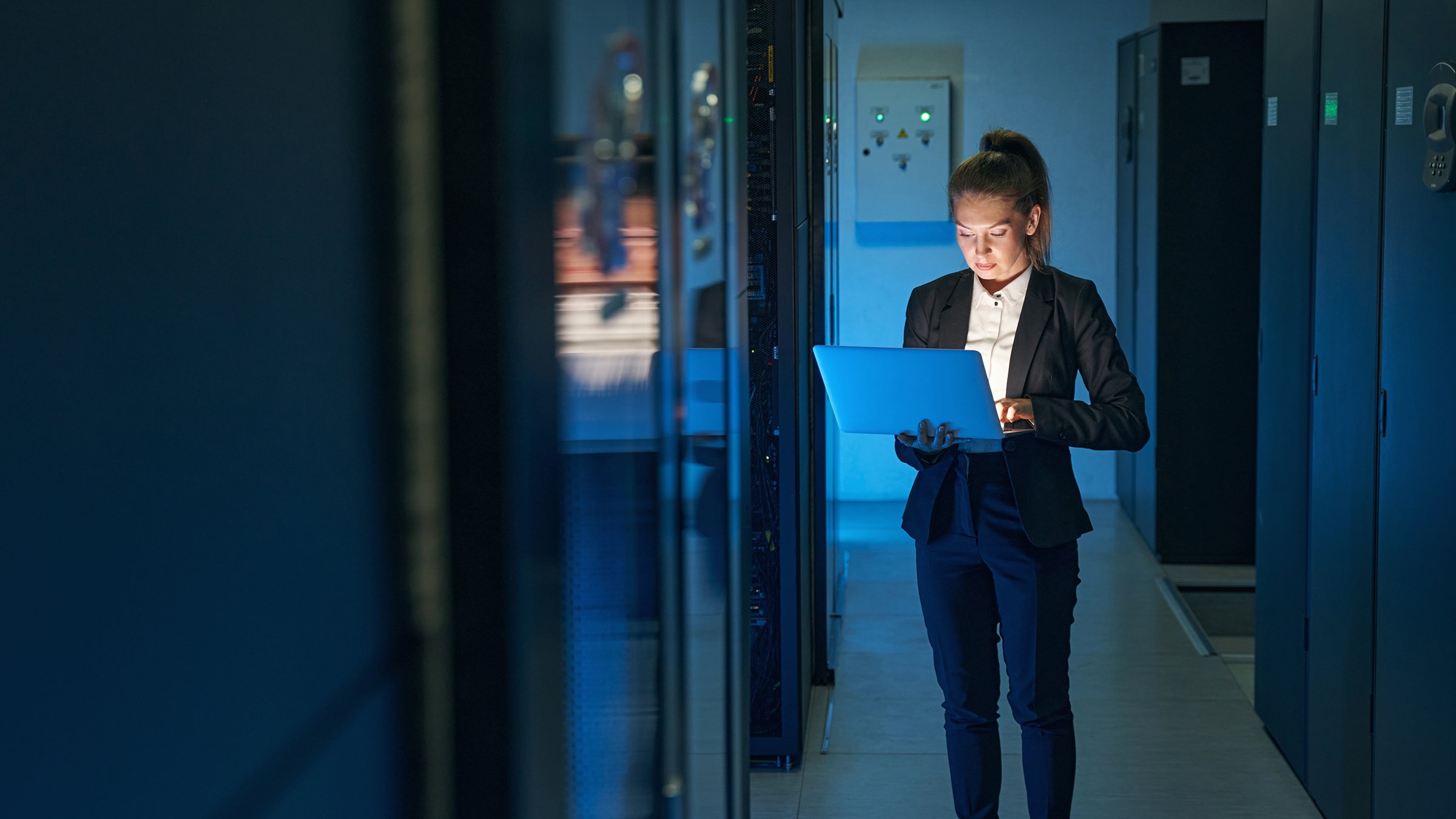 Young woman IT engineer use laptop computer while working with supercomputer in data center server room