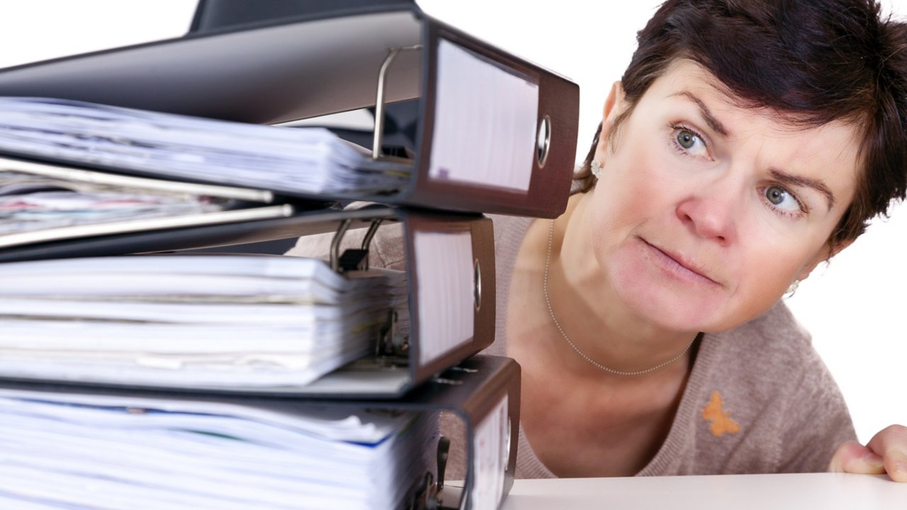 Woman closely looking at pile of binders full of papers