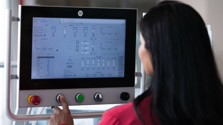 Woman with back turned presses button on Allen-Bradley HMI device