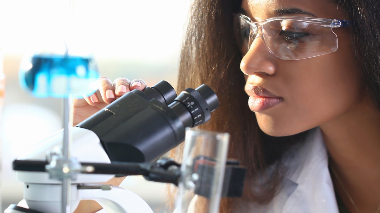 Female in lab looking into microscope