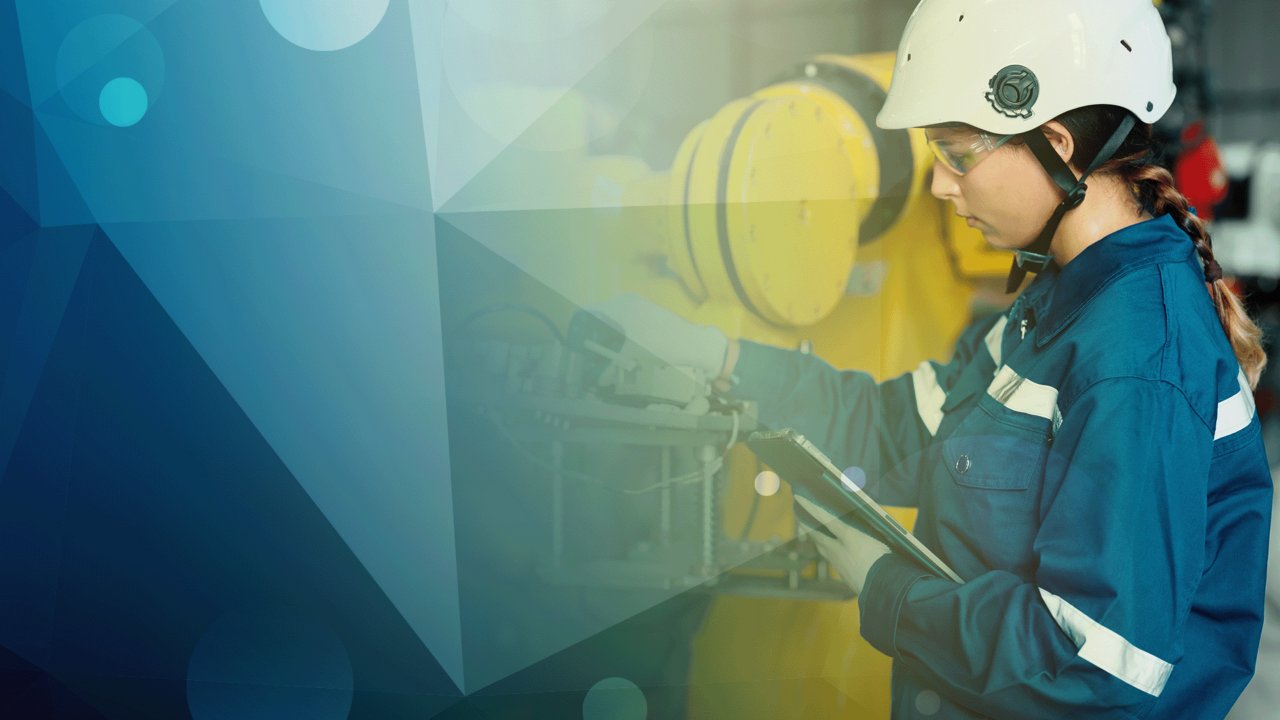 Worker in safety gear checking machine holding tablet