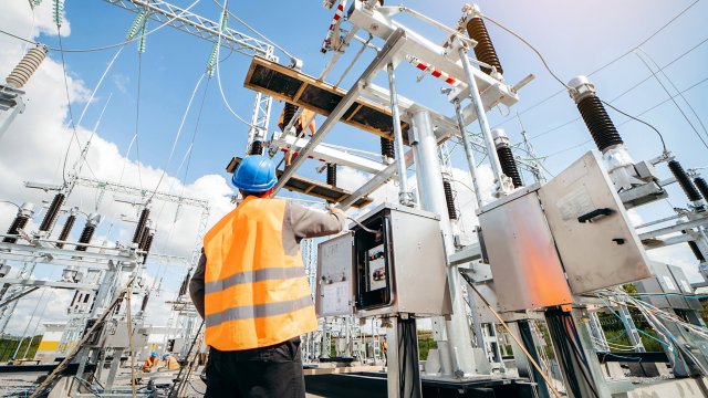 worker-in-hardhat-checking-on-large-power-transmission-equipment