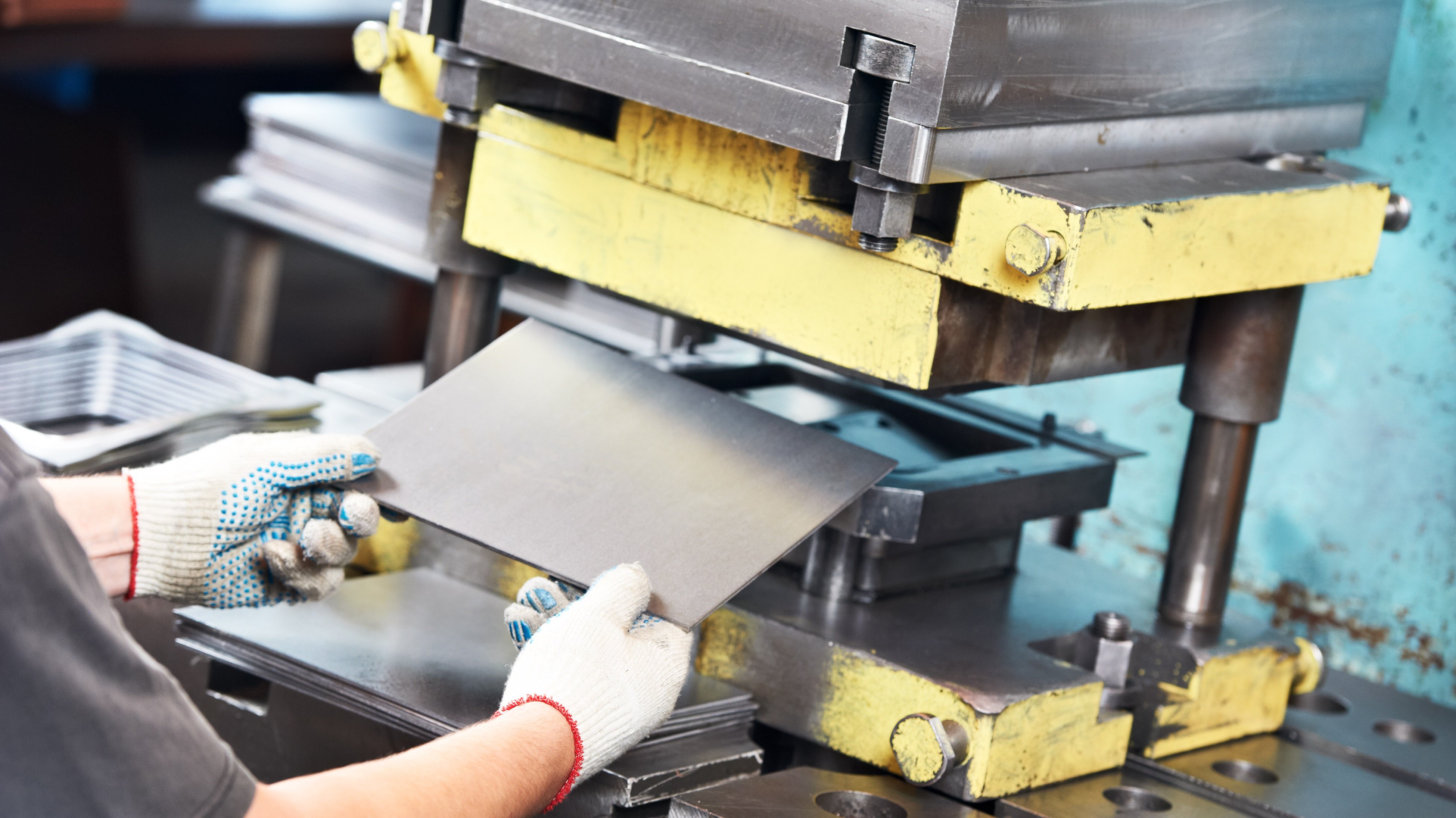 worker at manufacture workshop operating metal press machine