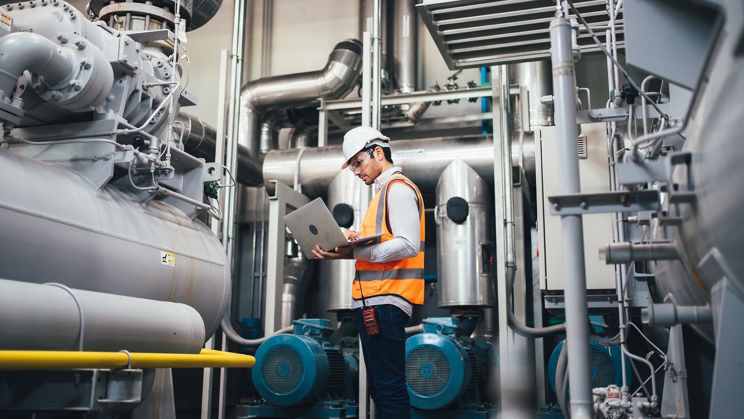 Professional worker of modern factory using laptop controlling program to automatic machinery. Engineering with laptop Programmable Logic Controller to manage large machine working full automatic.