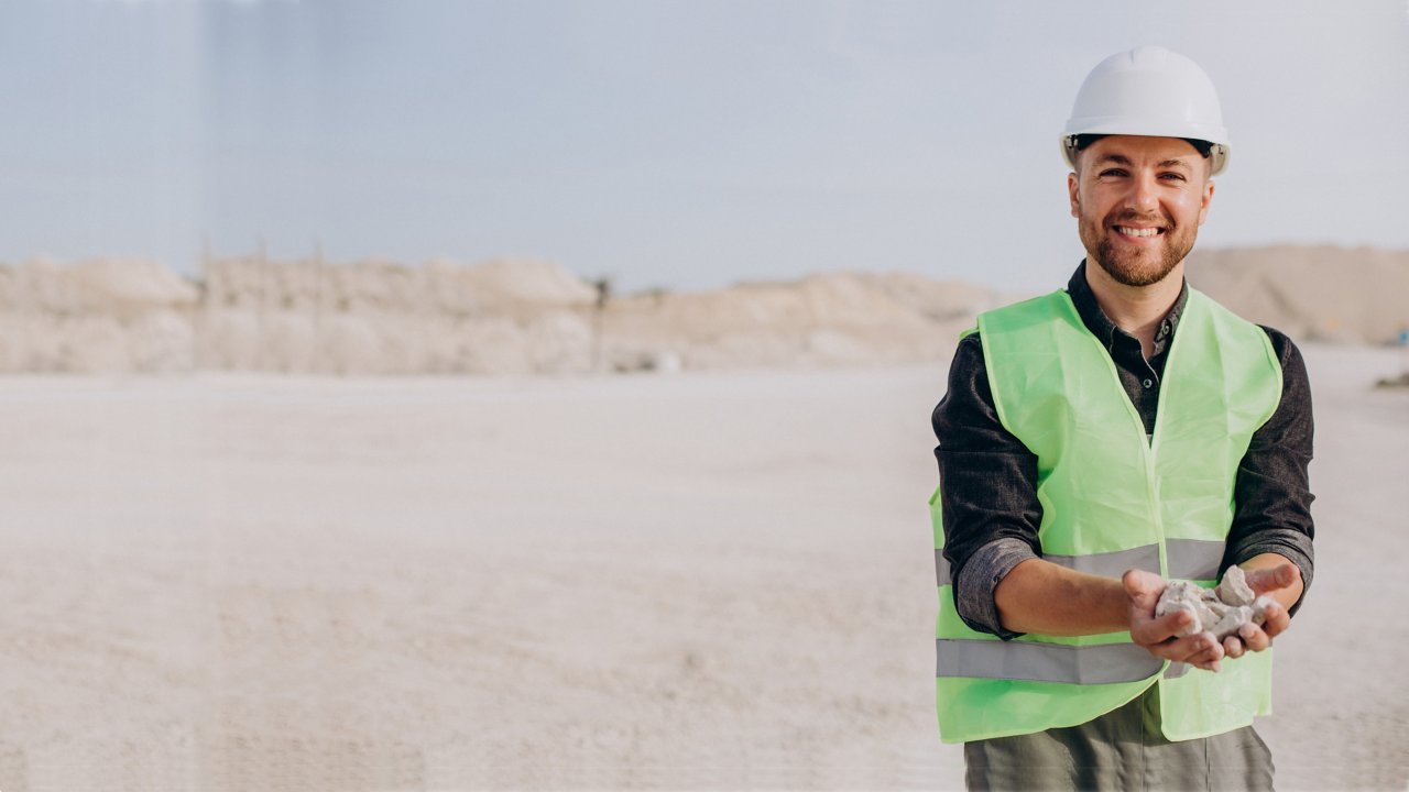 Worker in sand quarry holding rocks