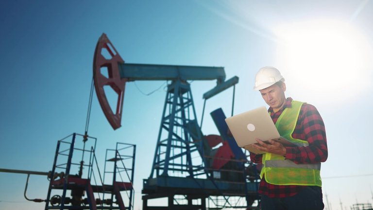 worker-with-laptop-standing-near-oil-and-gas-equipment