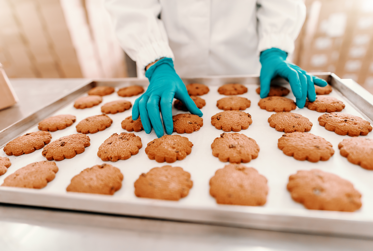 commercial baker inspecting cookies on sheet