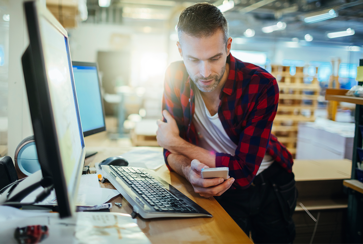 Man at office desk viewing mobile device
