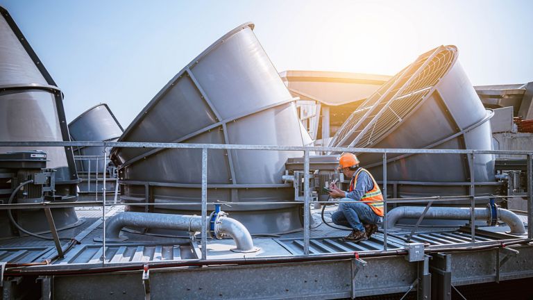 A engineer under checking the industry cooling tower air conditioner is water cooling tower air chiller HVAC of large industrial building to control air system