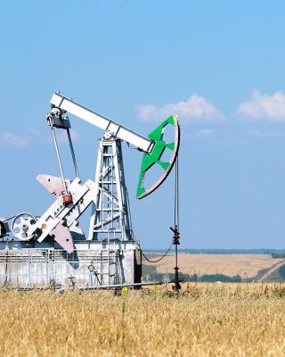 summer landscape oil pumps in the grain fields on the background of the blue sky on a sunny day