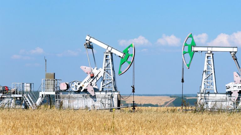 summer landscape oil pumps in the grain fields on the background of the blue sky on a sunny day