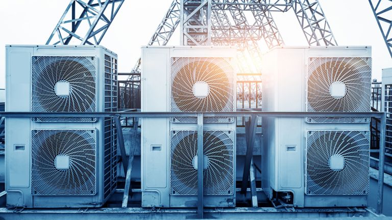 Air conditioner units HVAC on a roof of industrial building with blue sky and clouds in the background