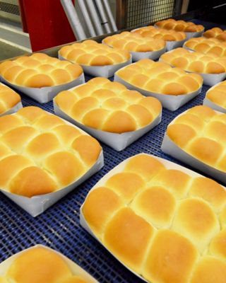 Trasportatore con panini al forno confezionati in contenitori di cartone bianco