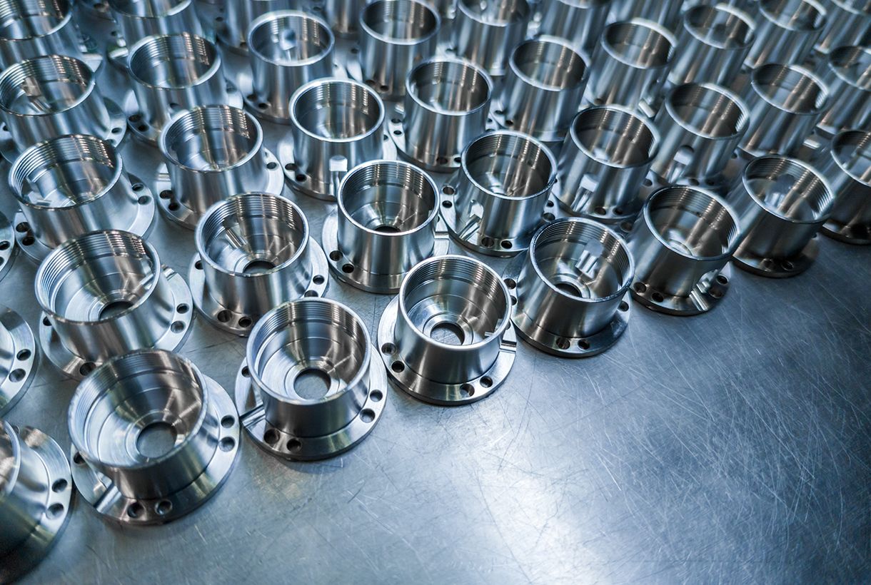 Shiny metal parts after cnc turning, drilling and machining on steel surface with selective focus for industrial background.