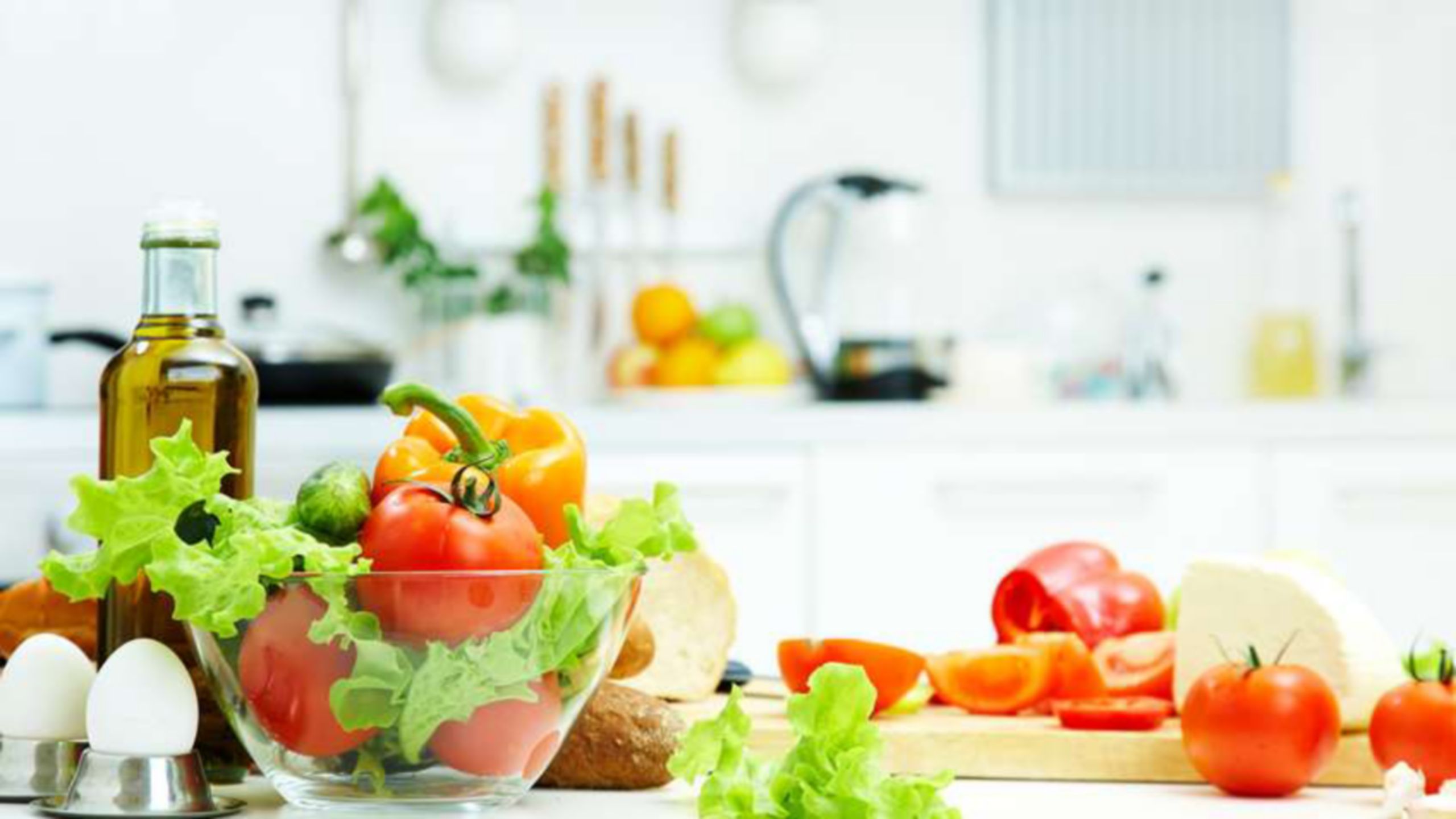 Zutaten für einen Salat, einschließlich Tomaten, Blattsalat und Eiern auf einer Küchentheke
