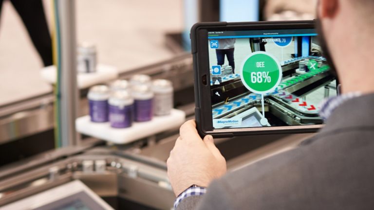 Trabalhador observa a tela de um tablet que mostra a análise da eficiência geral do equipamento