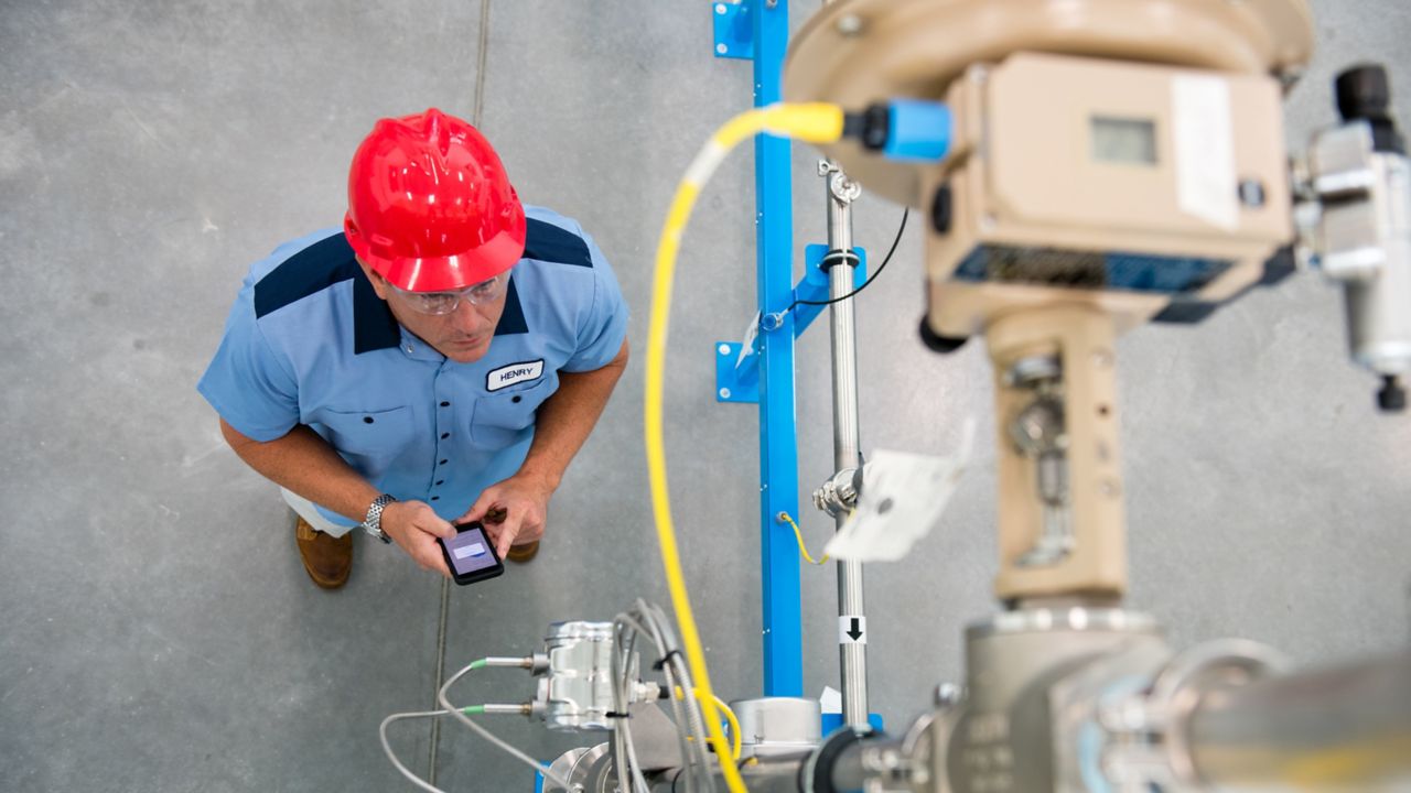 view from above of man in red hard hat looking up at a controller