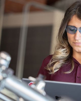 FactoryTalk PhamaSuite MES를 사용하여 생명 과학 산업 시설의 태블릿에서 데이터를 보는 여성 엔지니어