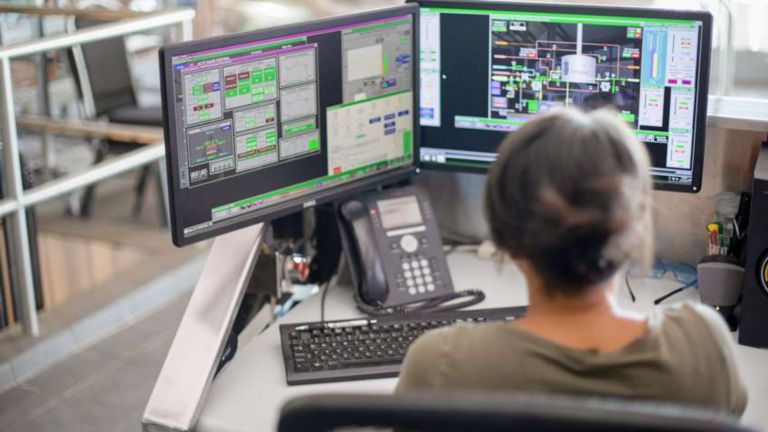 Une employée examine un aperçu des opérations en temps réel grâce à FactoryTalk Site Edition