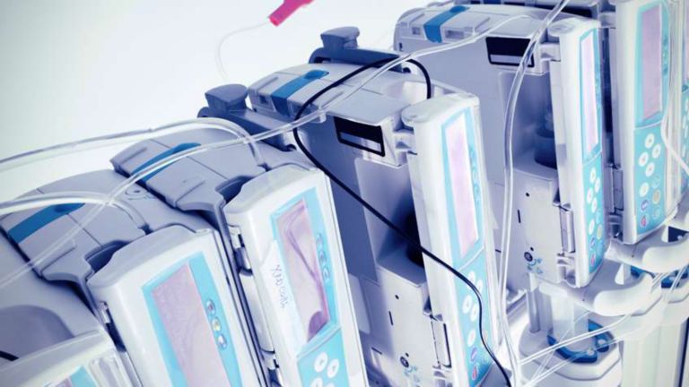 Un ensemble d'appareils de surveillance des patients, dont les tubes sortent par le haut, sont soigneusement alignés en vue d’être utilisés.