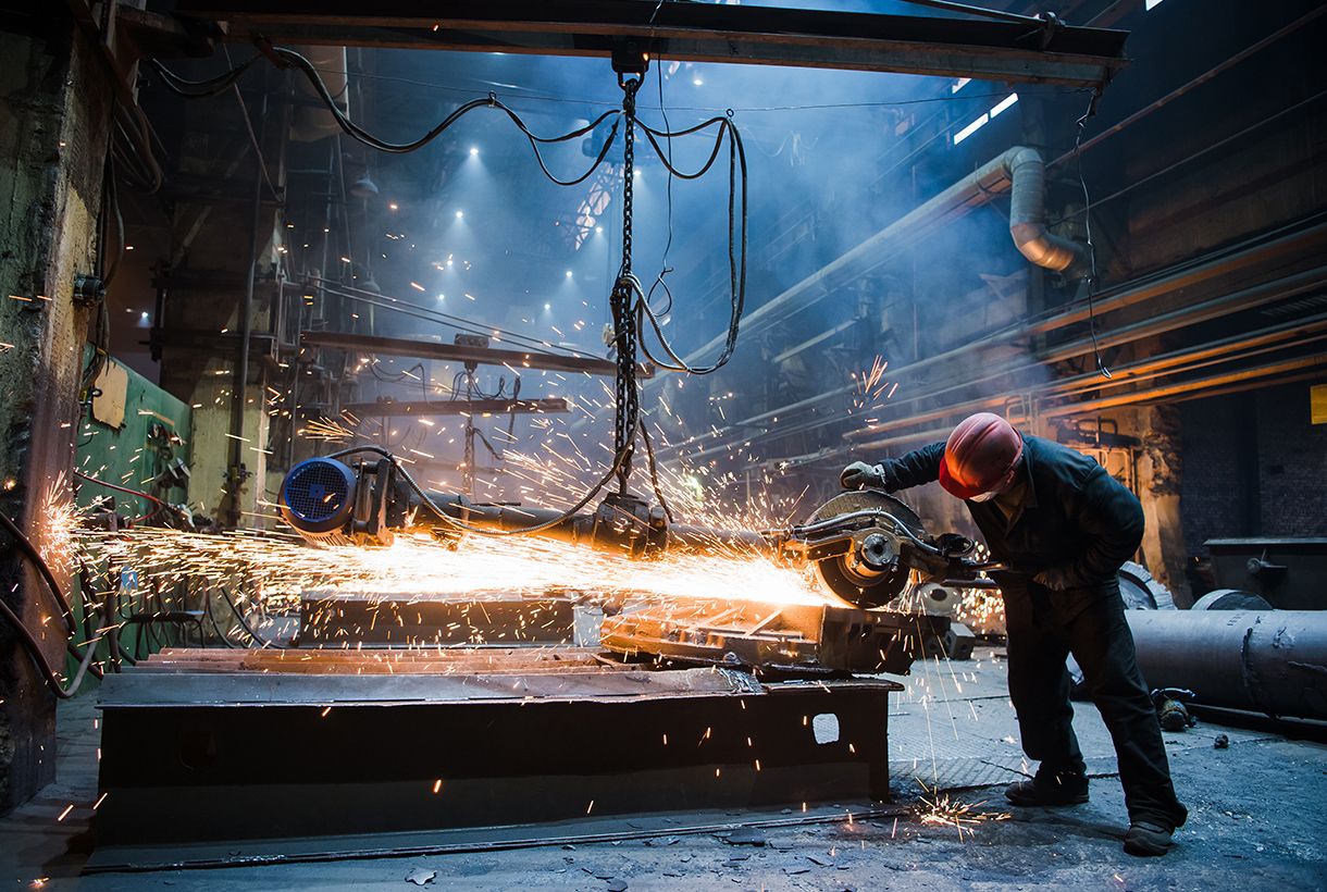 Employee grinding steel with sparks - focus on grinder. Steel factory
