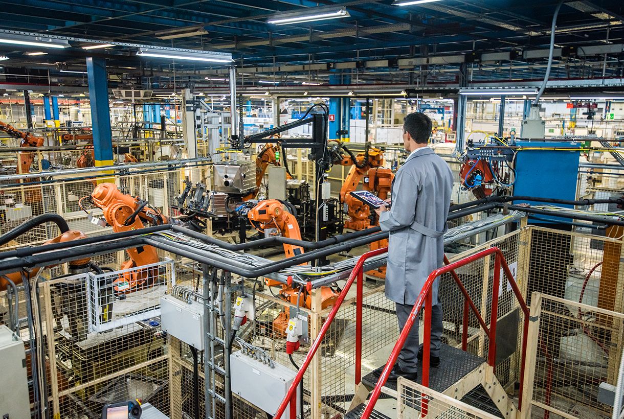 Male factory engineer inspecting the work process of the robots performing their operations in appliance manufacturing factory.