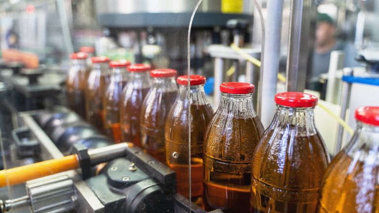 Garrafas de bebidas sendo conduzidas em um transportador de uma fábrica de bebidas