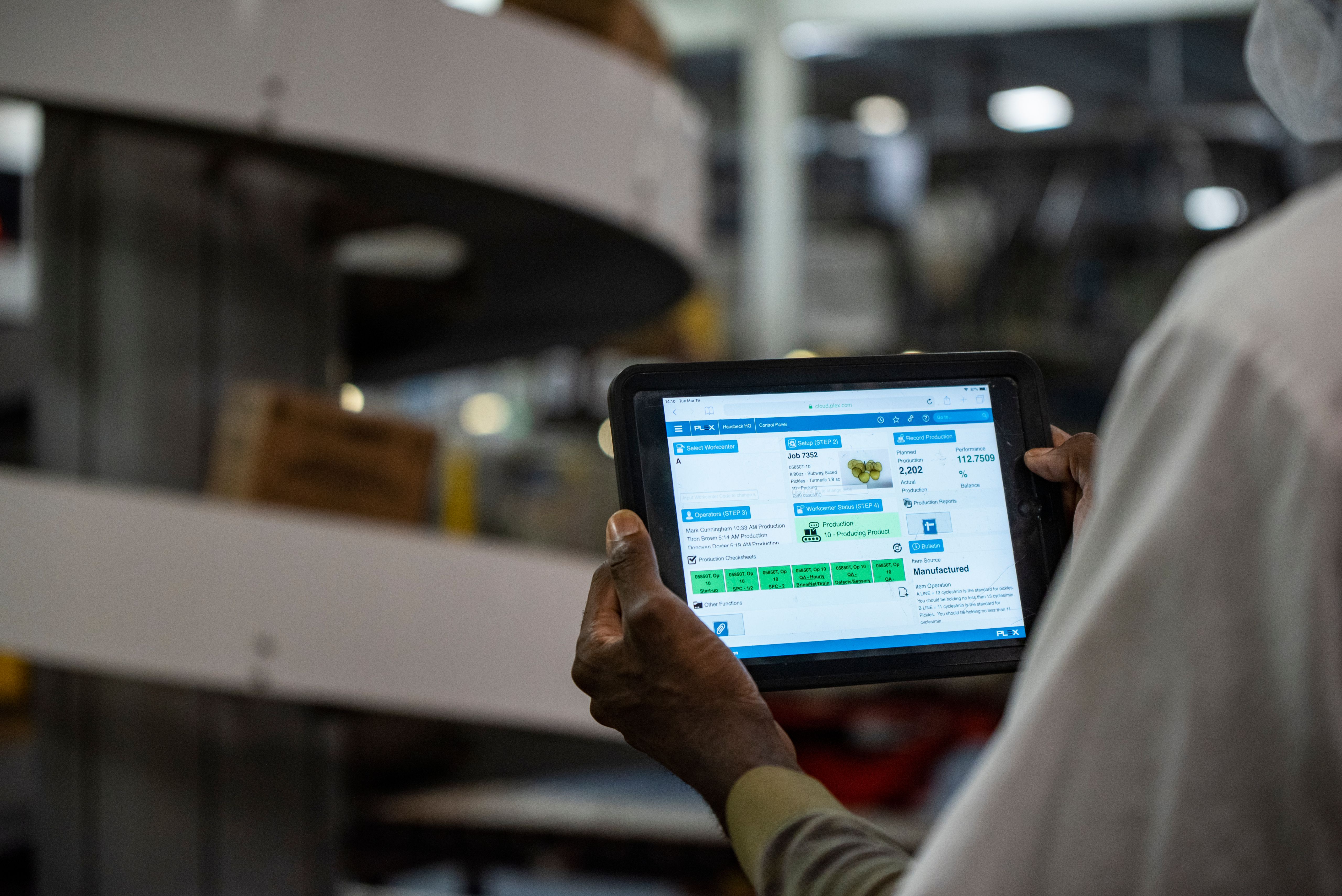 Plant worker on floor viewing tablet dashboard