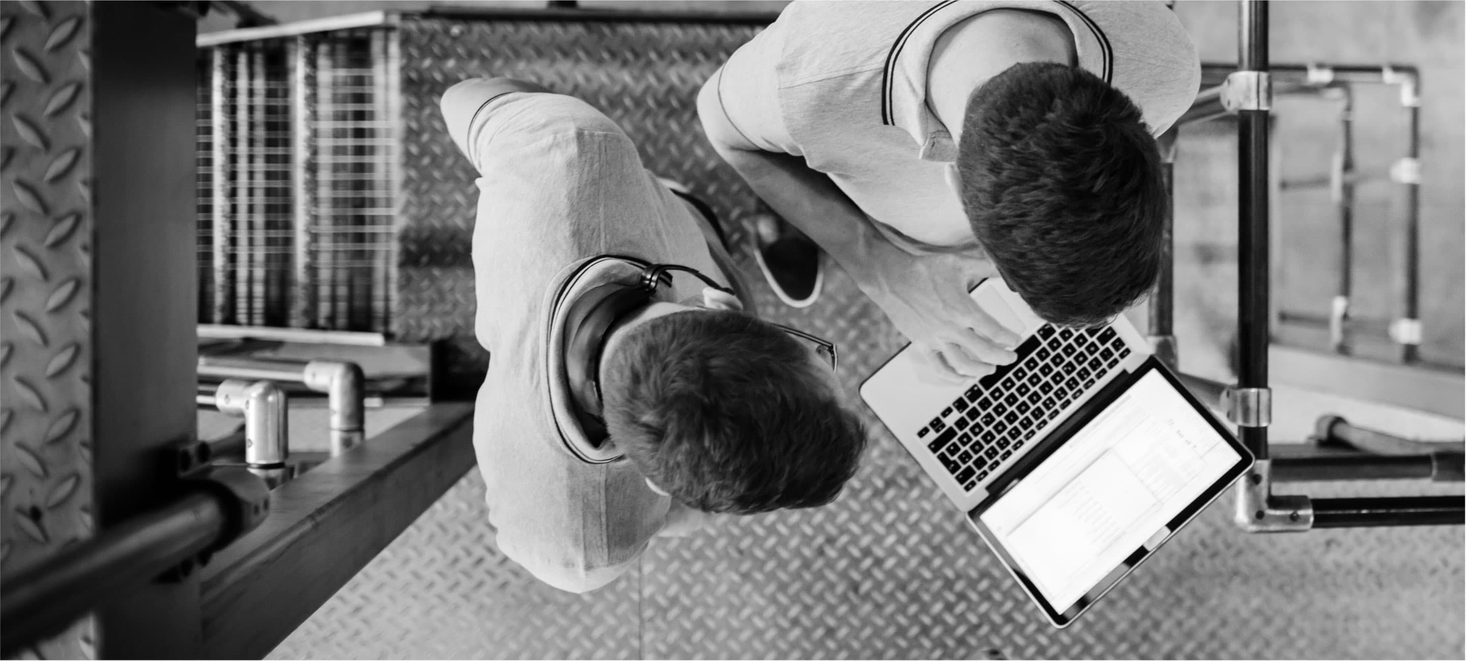 overhead view of two men working on a laptop