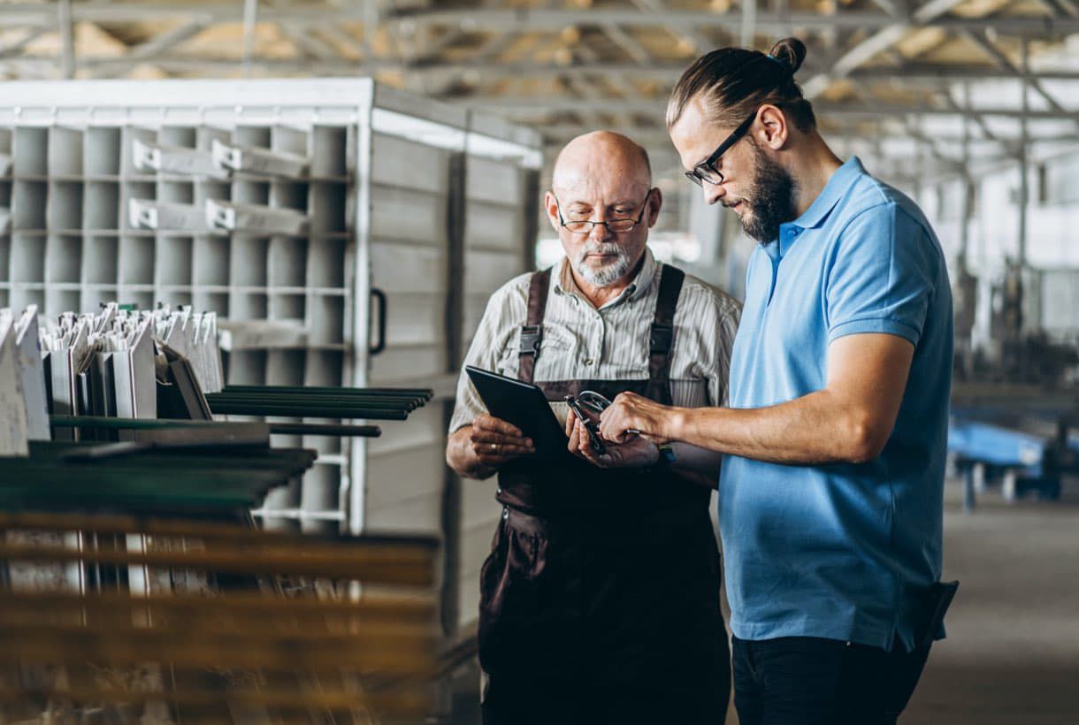 Two male plant workers collaborating over a shared tablet