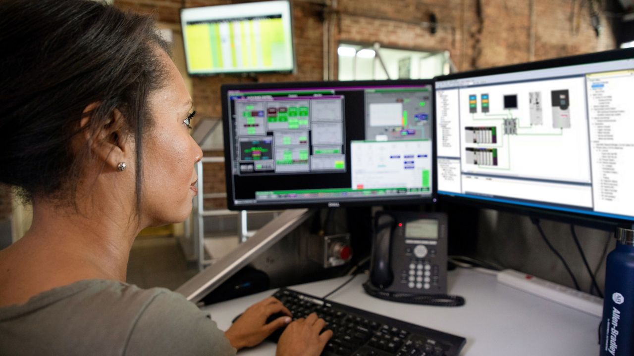 一名女性员工正在查看两台监视器，并将信息输入至软件应用程序