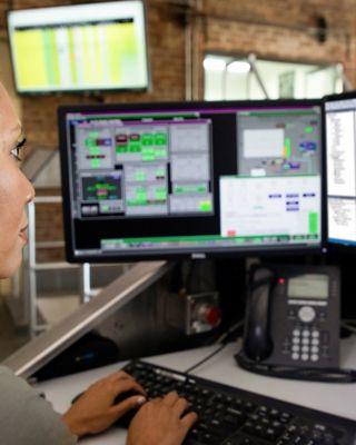 Mitarbeiterin, die auf zwei Monitore schaut und Informationen in eine Software-Anwendung eingibt