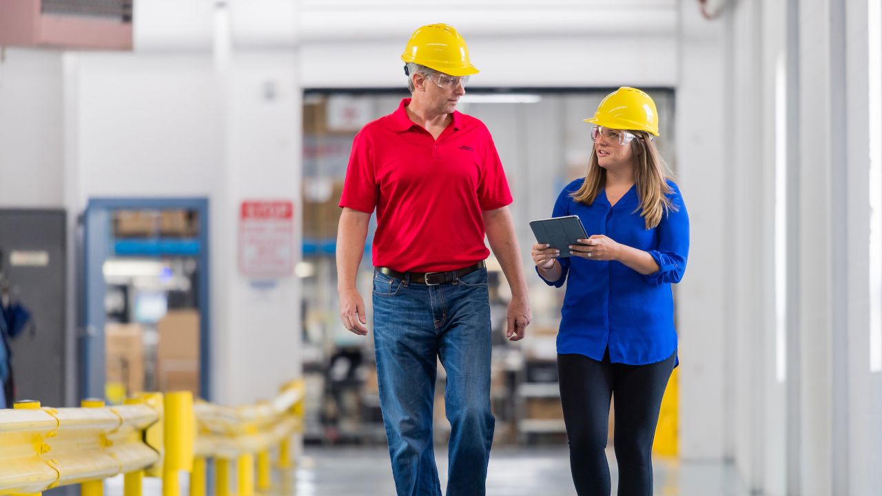 Colleagues with helmets talking with each other with tablet in hand.