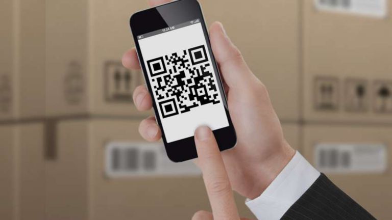 Close-up of hand holding a mobile phone that displays a QR code.