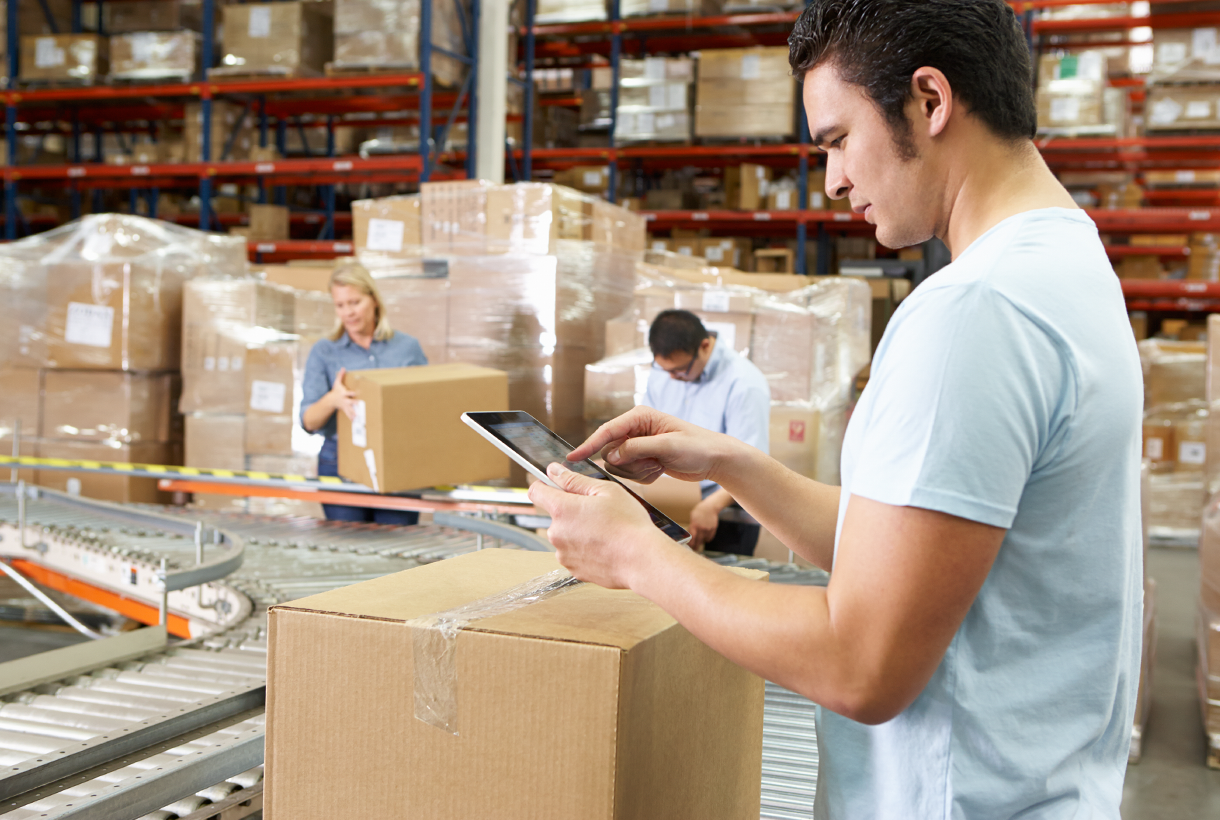Man at packaging conveyor with tablet device in hands