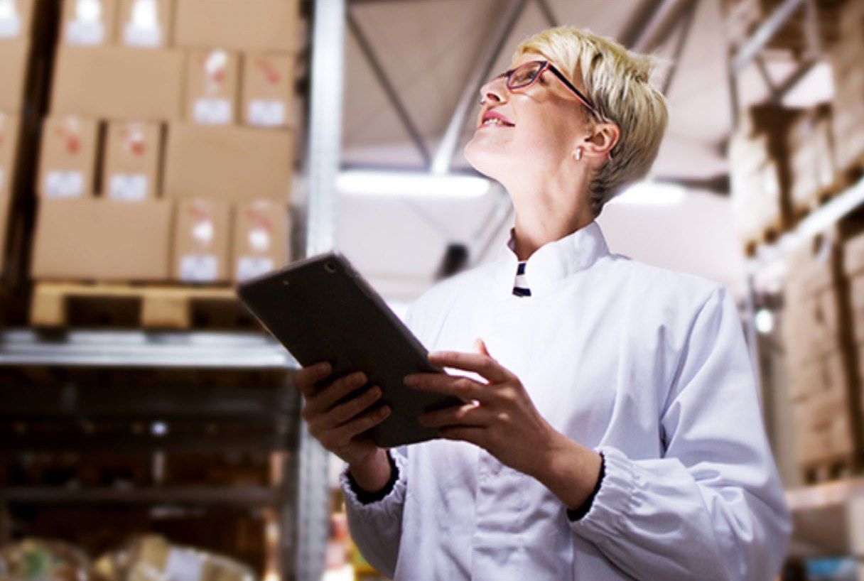 woman holding tablet in a warehouse surrounded by packages