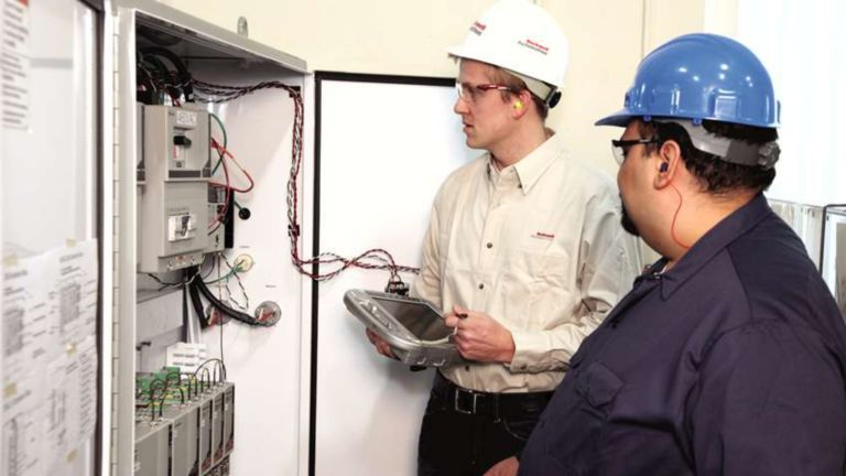 Dos empleados de Rockwell Automation recopilando datos del interior de un panel
